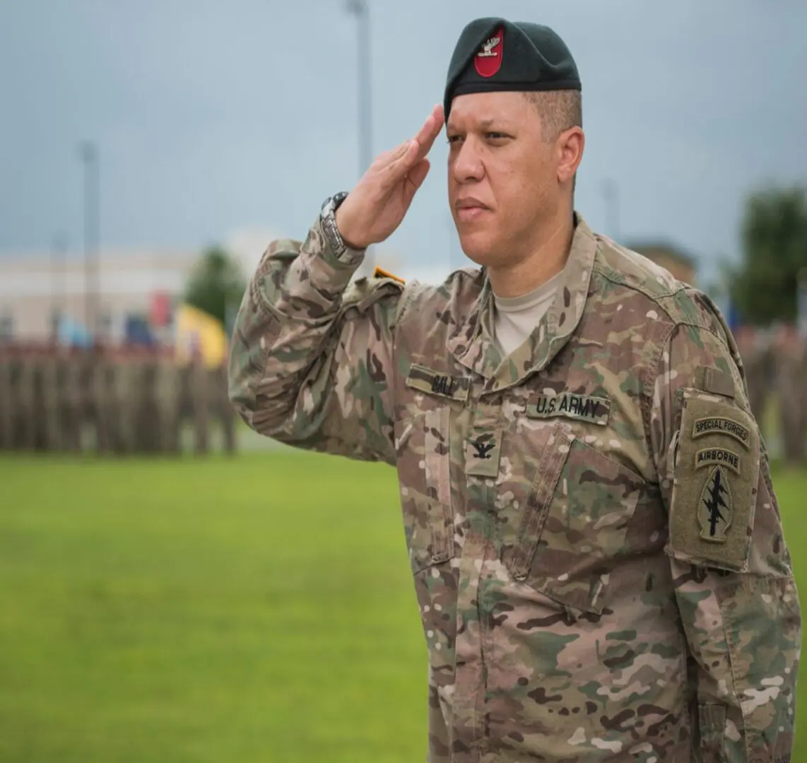 A soldier saluting while standing in front of other soldiers.