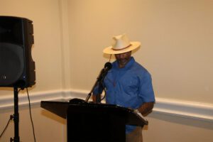 A man in a cowboy hat is speaking at a podium.