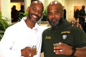 Two men are holding drinks and smiling for a picture.