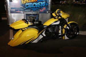 A yellow and white motorcycle parked in front of a building.