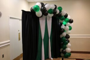 A green and white balloon arch with drapes