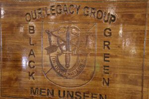 A wooden sign with the words black men unseen and the crest of the 1 0 th special forces group.