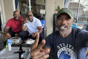 Three men sitting on a porch eating cake.
