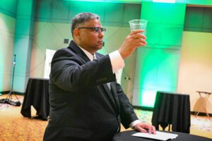 A man in a suit holding up a glass of water.