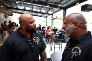 Two men in black shirts talking at a restaurant in color image