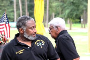 Two men in black shirts standing next to each other in color