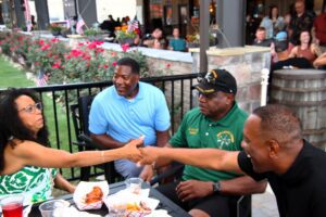 A group of people shaking hands at an outdoor restaurant.