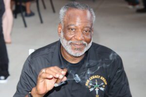 A man in a black shirt smoking a cigar and smiling image