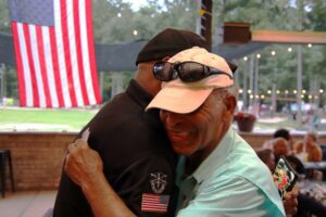 Two men hugging in front of an american flag.