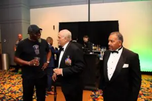 Three men in tuxedos talking to each other at an event image