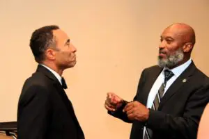 Two men in suits talking to each other in color image section